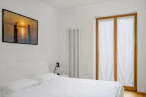 a white bedroom with a bed and a window at Windshouse 2 Apartments in Nago-Torbole