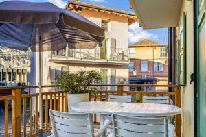 a table and chairs on a balcony with an umbrella at Windshouse 2 Apartments in Nago-Torbole