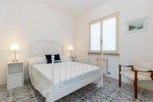 a white bedroom with a bed and a chair at La Caletta Di Luce in Lerici