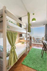 a bedroom with bunk beds with a green rug at Hostel Casa La Cha in Novalja