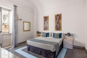 a bedroom with a bed and two paintings on the wall at Archimede Charm B&B - Historical Palace in Ortigia in Syracuse