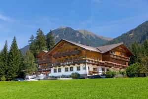 ein großes Gebäude auf einem Feld vor einem Berg in der Unterkunft Hotel Waldruhe in Gsies