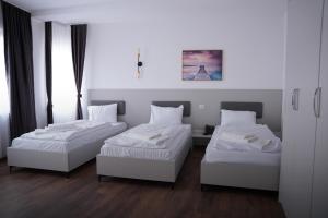 two beds in a room with white walls and wood floors at Hotel Joana in Prizren