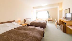 a hotel room with two beds and a desk at グリーンピア三陸みやこ in Miyako +3 photos