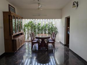 a dining room with a table and chairs and plants at Veranda Villa in Angamaly