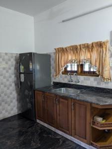 a kitchen with a sink and a refrigerator at Veranda Villa in Angamaly +3 photos