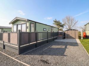 a green house with a fence and a yard at Lodge 22, Moselle in Malton