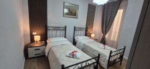 two beds in a room with two lamps and a window at Casa di Clara in Sulmona