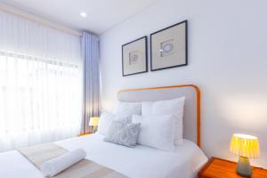 a bedroom with a bed with white sheets and a window at Elle Apartments in Lusaka +16 photos