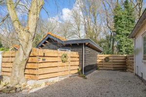 a house with a wooden fence next to a tree at Studio Oak & Studio Linde in Aerdenhout