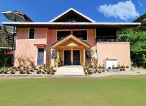 a house with a green lawn in front of it at The Bay Leaf Resort in Shimla