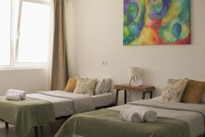 a room with two beds and a painting on the wall at The Tree House Tenerife in El Médano +69 photos