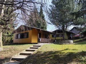 a small yellow house with stairs in a yard at středisko Doubrava in Zlaté Hory