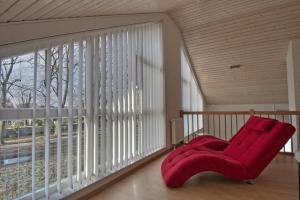 a red chair sitting in front of a large window at Ferienhaus Luan in Nordhorn +3 photos