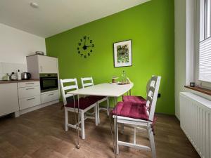 a kitchen with a table and chairs and a green wall at Dorle`s Huus in Nordhorn