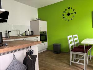 a kitchen with a green wall with a clock on it at Dorle`s Huus in Nordhorn