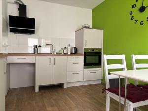 a kitchen with white cabinets and a green wall at Dorle`s Huus in Nordhorn +11 photos