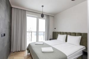 a bedroom with a bed with white sheets and a large window at Willa Zieleniec - apartamenty z Ogrodem SPA in Duszniki Zdrój