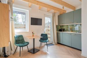 a kitchen with a table and two green chairs at Studio Oak & Studio Linde in Aerdenhout