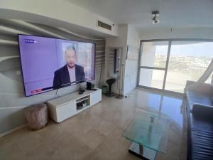 a living room with a large flat screen tv on the wall at מרינה טוורס מלון בוטיק in Herzliya B