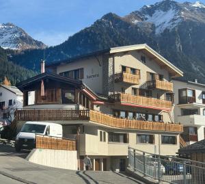 a large building with balconies and a van parked in front at Design-Studio nahe der Piste Lenzerheide in Lenzerheide