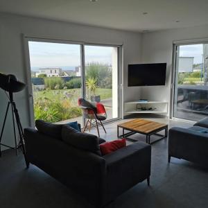 a living room with a couch and a table at La Belle Vue Piscine chauffée et abritée, vue sur l'océan, plage à pied, bord de mer, BRETAGNE LBC in Clohars-Carnoët