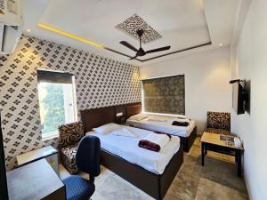 a bedroom with two beds and a table and chairs at Hotel Akashdeep in Kolkata