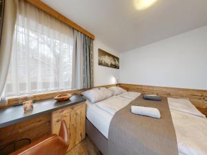 a bedroom with a bed and a desk and a window at Pension Rainer in Ellmau