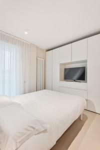 a white bedroom with a large bed and a flat screen tv at Magnolia Studio Appartamento Marina di Carrara in Marina di Carrara
