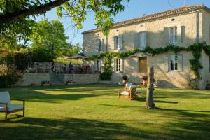 a large stone house with people sitting in a yard at Plates Luxury Farm House Chambres d'hôtes et gîte in Saint-Mézard