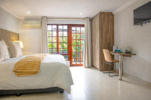 a bedroom with a bed and a desk and a window at Apple Blossom Hotel Portfolio in Roodepoort