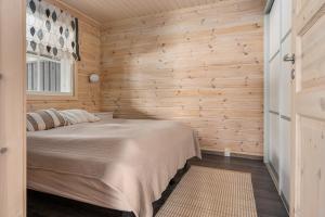 a bedroom with a bed in a room with wooden walls at Skicamp 3 - Modern 3BR Villa in Pyhätunturi in Pyhätunturi