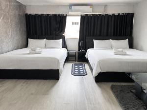 two beds in a hotel room with white sheets at popular condo c5 แม่ตัง in Thung Si Kan
