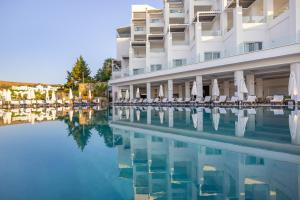 a hotel swimming pool with chairs and a building at La Quinta by Wyndham Bodrum in Bodrum City