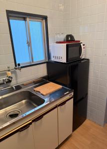 a kitchen with a sink and a microwave at 亀井町Stay201 in Takamatsu