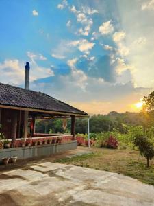 a house with the sunset in the background at Tayra - The Glass Villa in Somvārpet