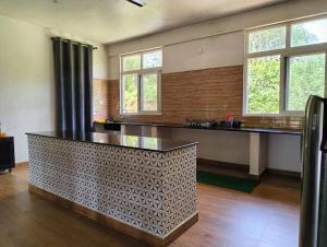 a large room with a counter and some windows at Tayra - The Glass Villa in Somvārpet