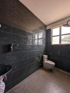 a black bathroom with a toilet and a sink at Tayra - The Glass Villa in Somvārpet +15 photos