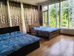 a bedroom with two beds and a large window at Tayra - The Glass Villa in Somvārpet
