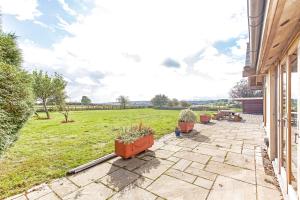 a patio with potted plants and a grass field at Amber Lodge in Ashover +3 photos