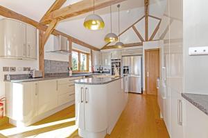 a kitchen with white cabinets and wooden ceilings at Amber Lodge in Ashover