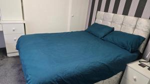a bed with blue sheets and blue pillows in a bedroom at Double room in Reading in Earley