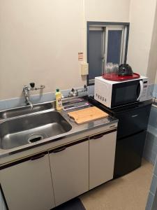 a kitchen with a sink and a microwave at 亀井町Stay202 in Takamatsu