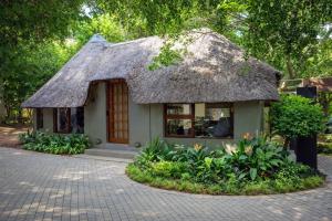 a small house with a thatched roof at Apple Blossom Hotel Portfolio in Roodepoort