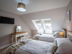 a bedroom with two beds and a desk and two windows at 3 Bed in Seahouses oc-81486 in Seahouses