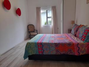 a bedroom with a bed with a colorful blanket and a window at Do-Little Cottages in Port Edward