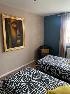 a bedroom with two beds and a painting on the wall at Bienvenue chez Virginie in Pontorson