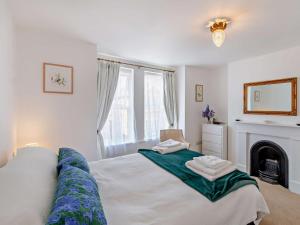 a bedroom with a large white bed with a fireplace at 2 Bed in Bembridge oc-94115 in Bembridge