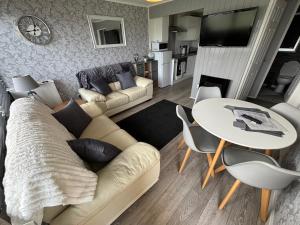 a living room with a couch and a table at 58, Two bed chalet on Sund0wner Holiday Park - Sleeps 4, pet friendly - Free WiFi plus electricity all included - Entertainment options close by in Hemsby
