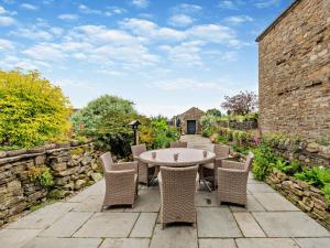 a patio with a table and chairs and a stone wall at 3 Bed in Leyburn oc-76395 in Askrigg